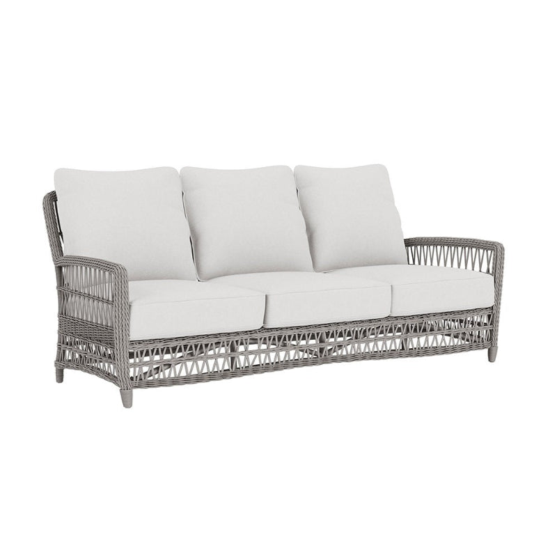 Gray wicker outdoor sofa with white cushions on a white background