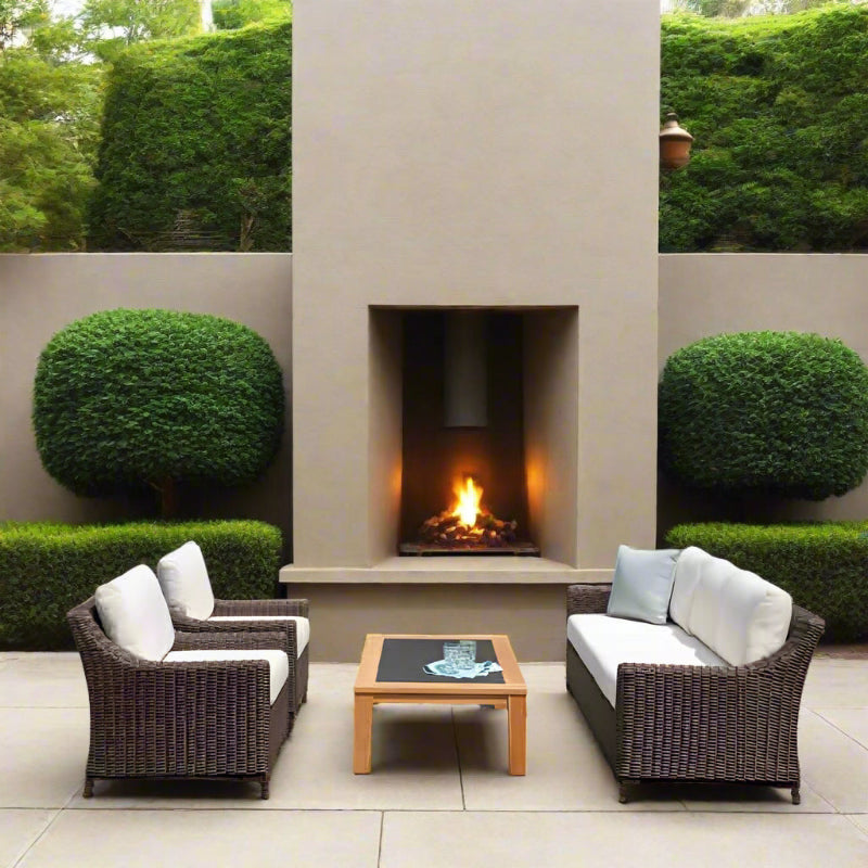 Outdoor patio set with wicker chairs and table in front of a stone fireplace.