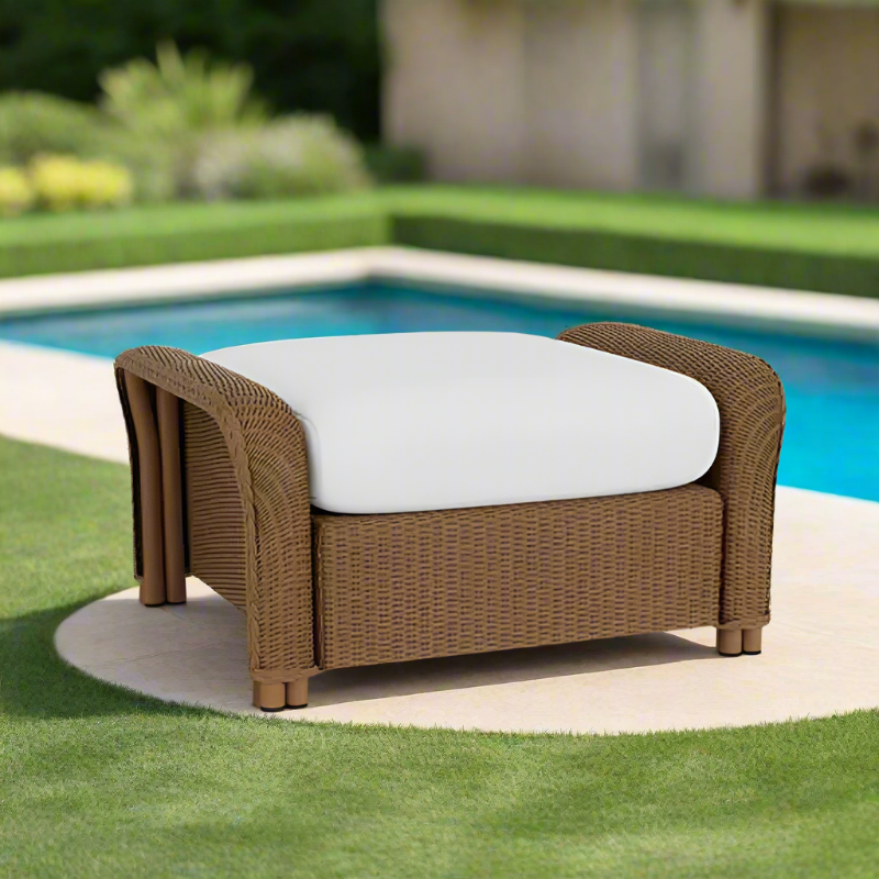 Brown wicker chair with a white cushion by a poolside