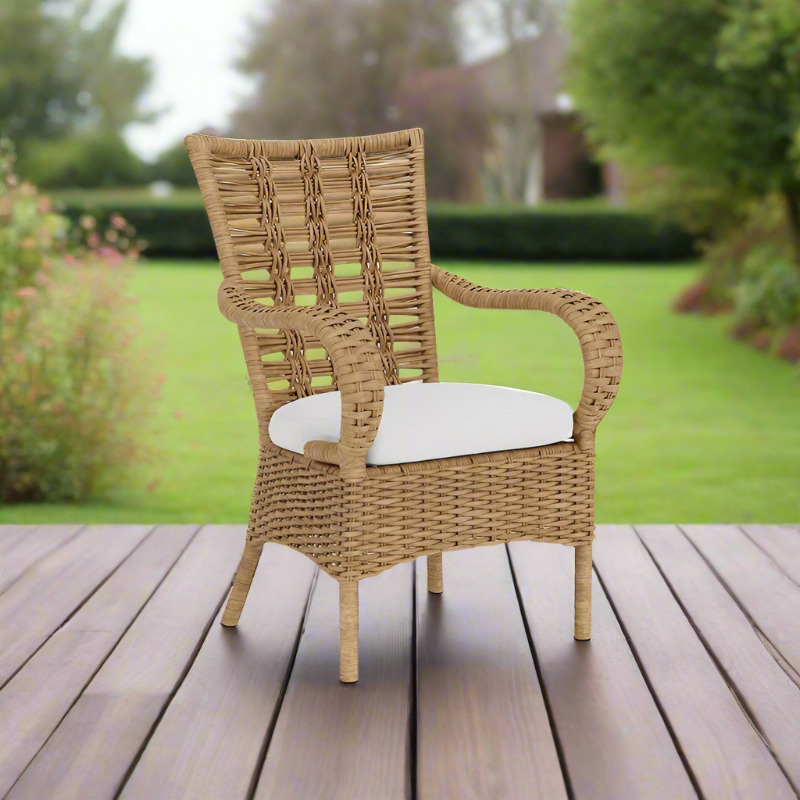 Wicker chair with a white cushion on a wooden deck with a garden background