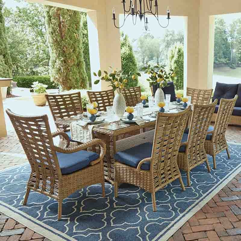 Outdoor dining set with wicker chairs and blue cushions on a patio.