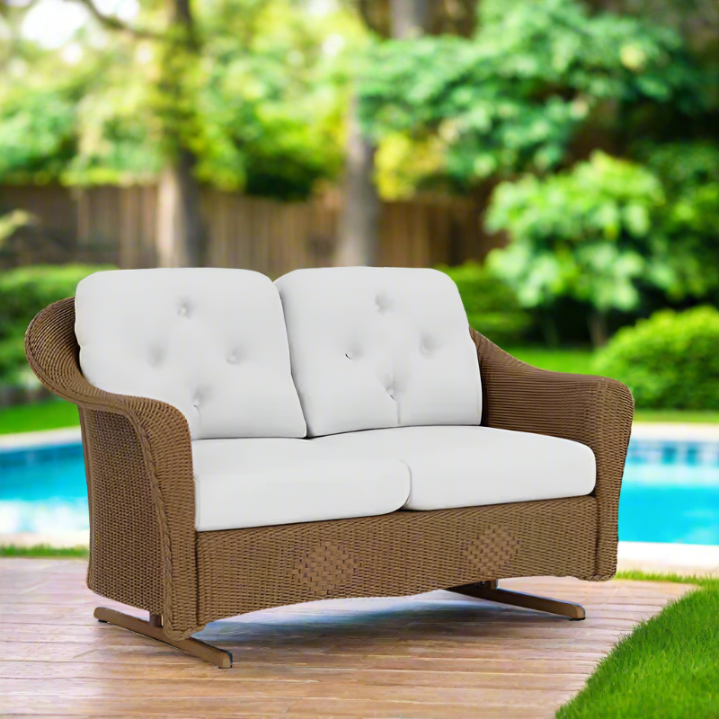 Brown outdoor loveseat with white cushions on a wooden deck by a pool