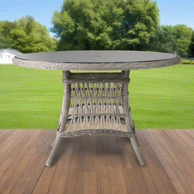 Round outdoor dining table with wicker base on a wooden deck