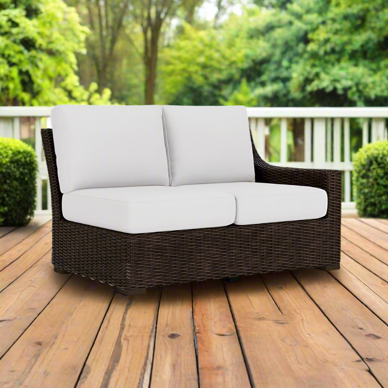 Wicker outdoor sofa with white cushions on a wooden deck