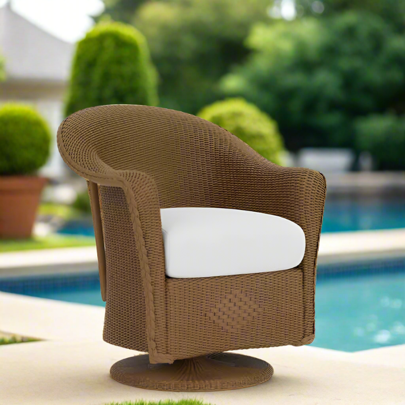 Brown wicker chair with a white cushion by a poolside