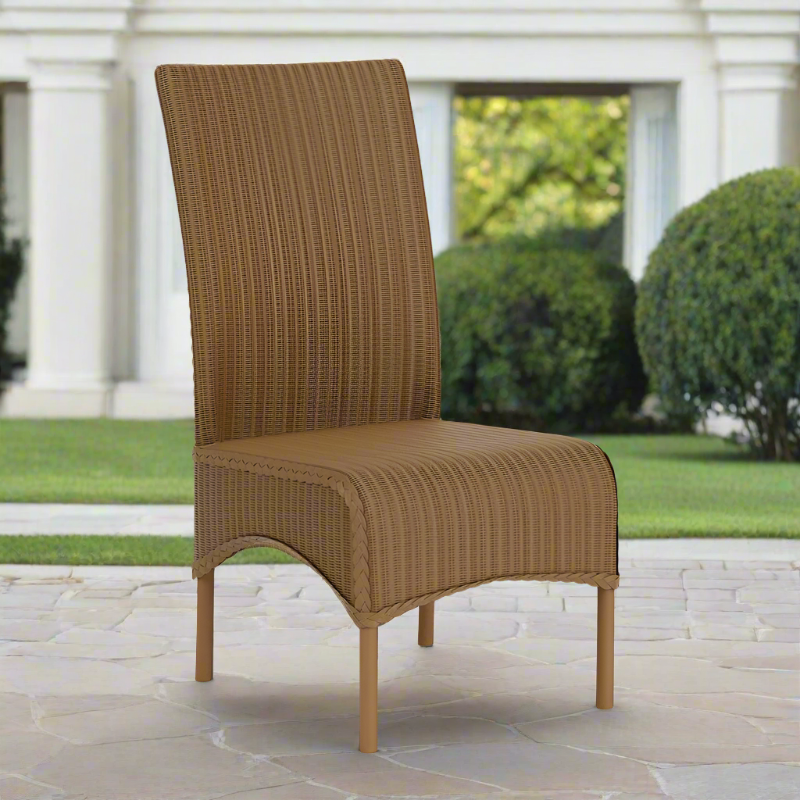 Brown wicker chair on a stone patio with a garden background