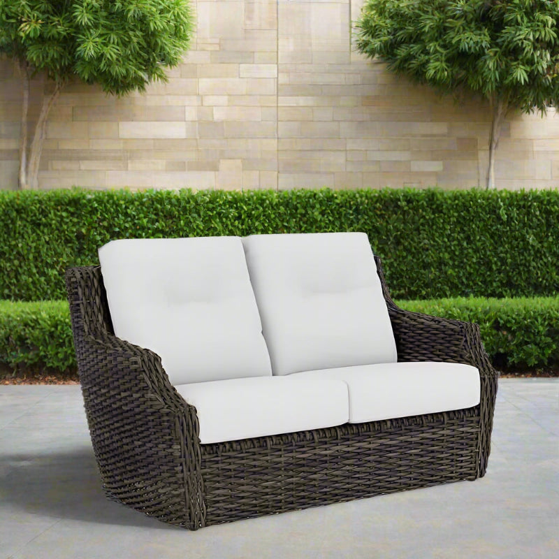Wicker outdoor sofa with white cushions on a white background