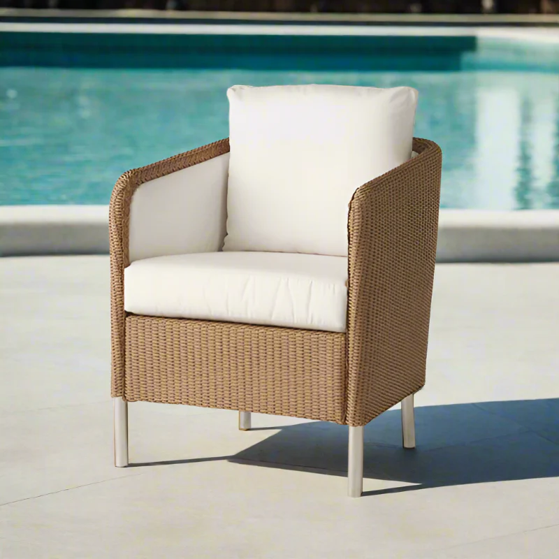 Wicker chair with white cushions by a pool