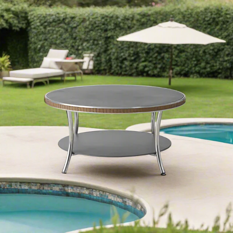 Round outdoor table with a pool and lounge chairs in the background