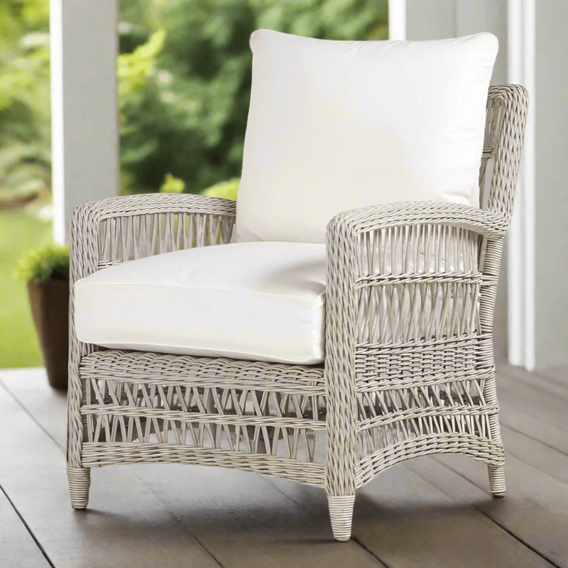 Wicker armchair with white cushions on a wooden deck