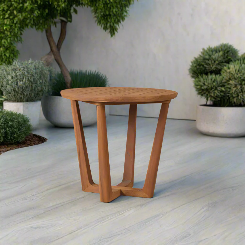 Wooden side table on a patio with potted plants in the background