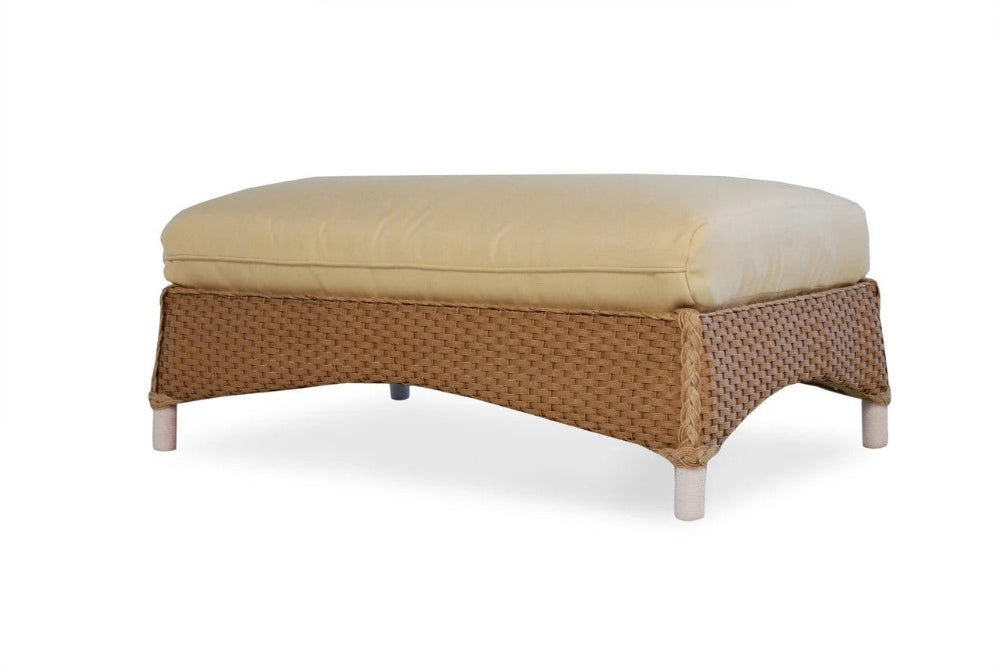 Wicker ottoman with beige cushion on a white background