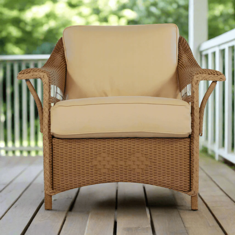 Wicker chair with beige cushions on a wooden deck