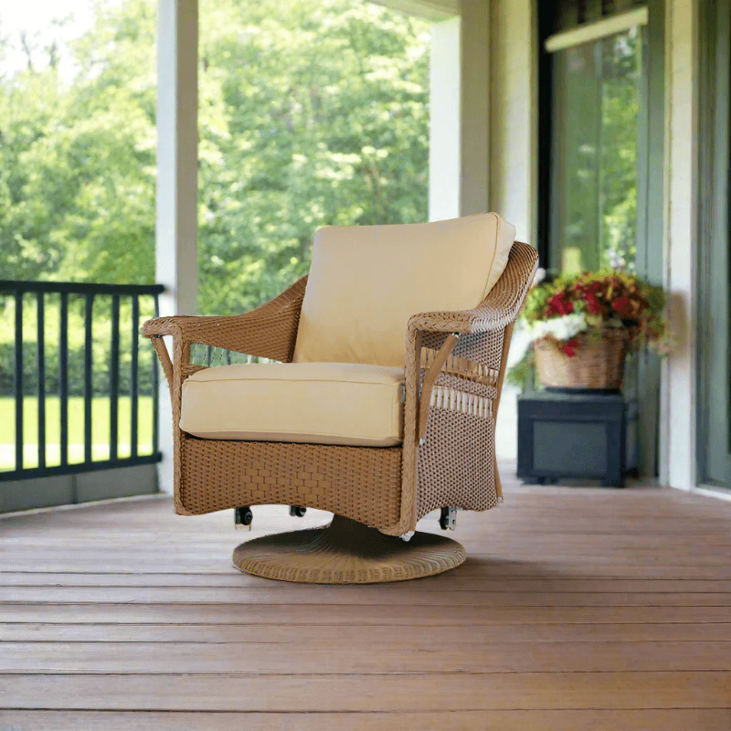 Wicker chair with beige cushion on a wooden deck with greenery in the background