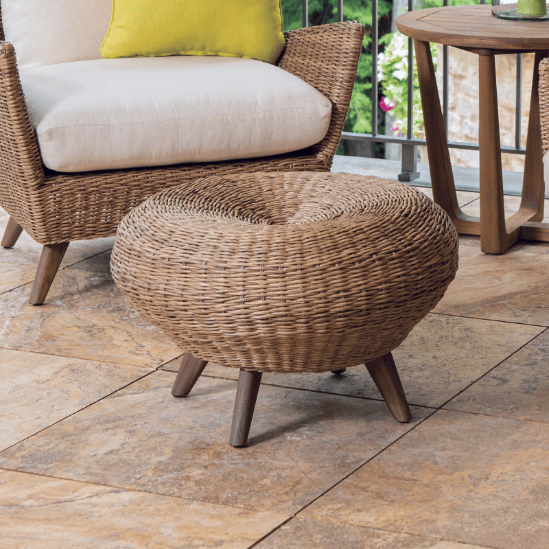 Wicker ottoman on a patio with a chair and table in the background