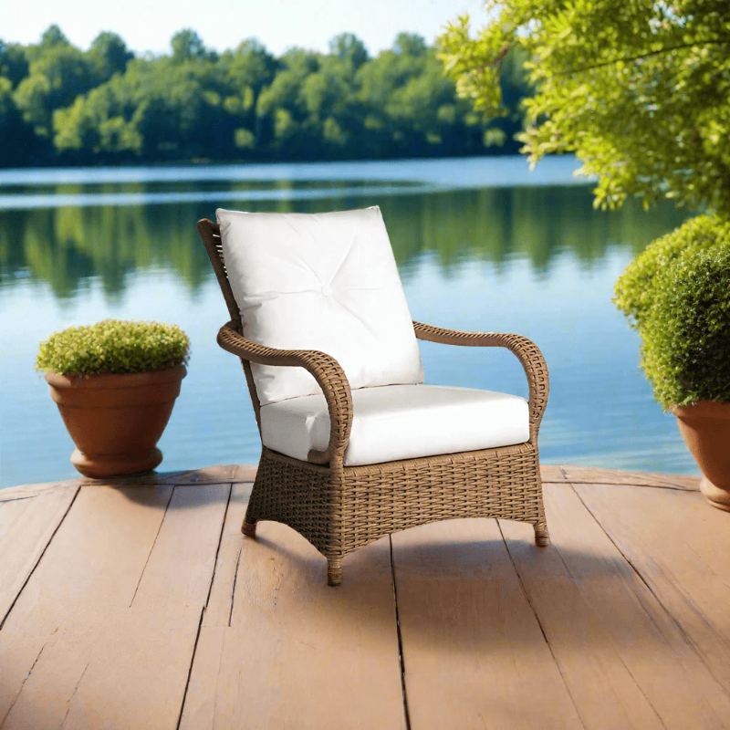 Wicker chair with white cushions on a wooden deck by a lake