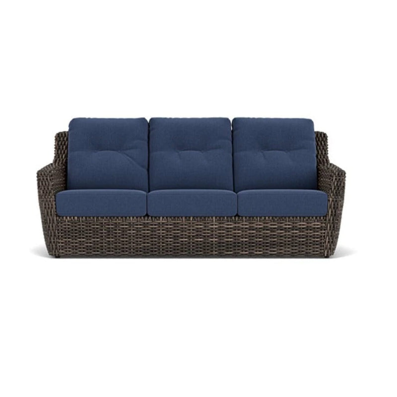 Wicker outdoor sofa with blue cushions on a white background