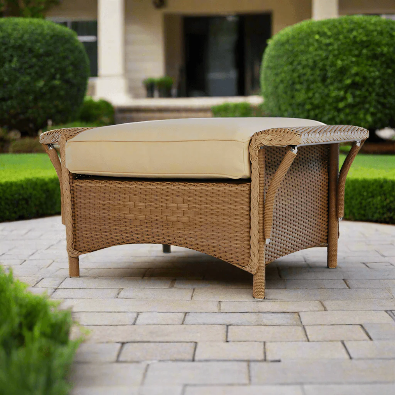 Wicker ottoman with beige cushion on a patio