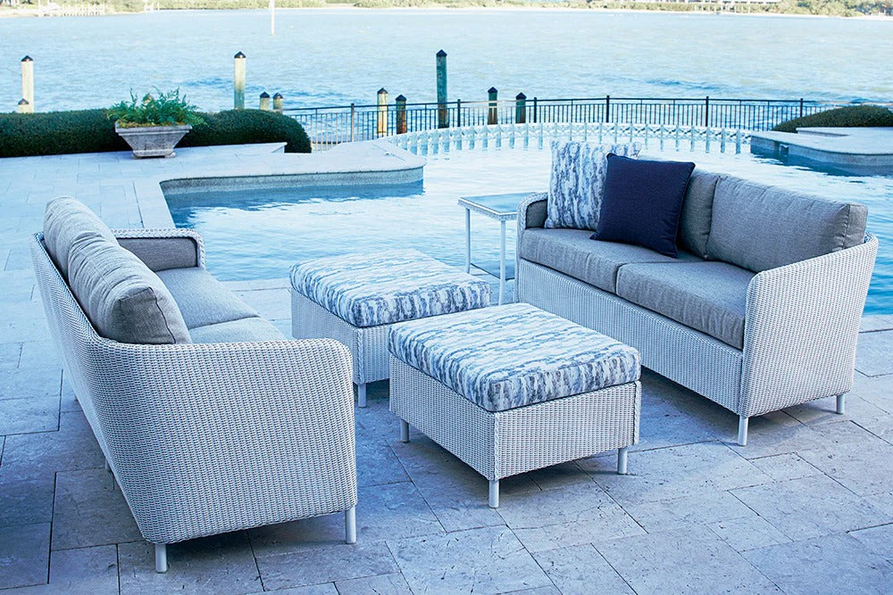 Outdoor patio furniture set with cushions by a poolside.