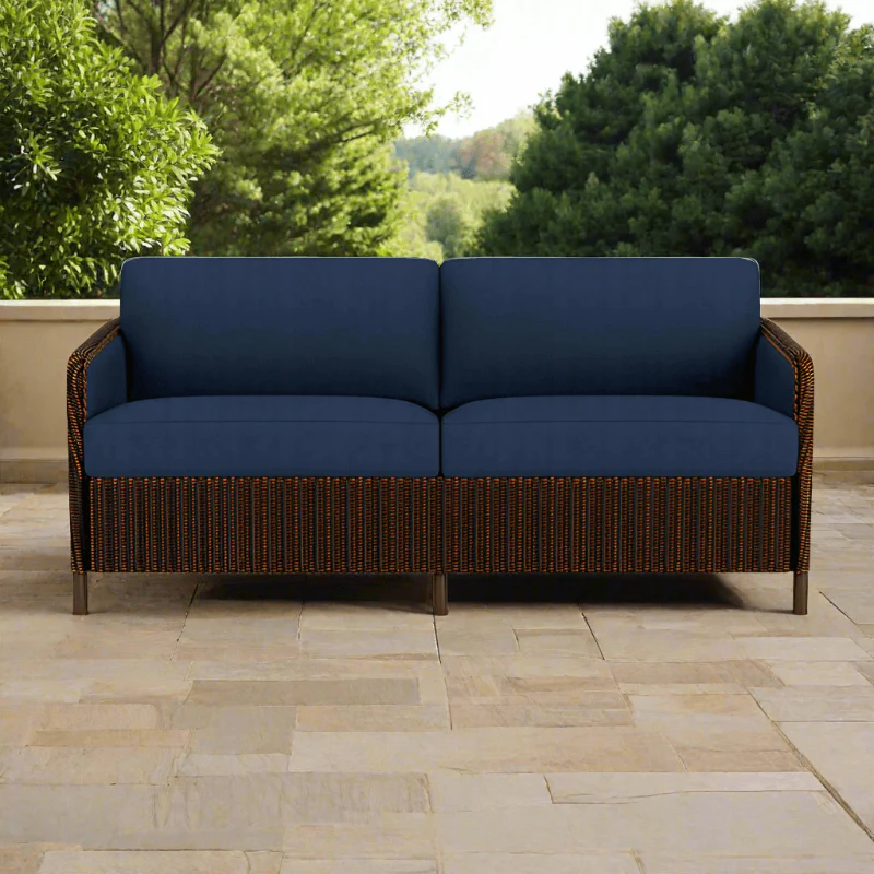 Outdoor sofa with blue cushions on a patio with greenery in the background