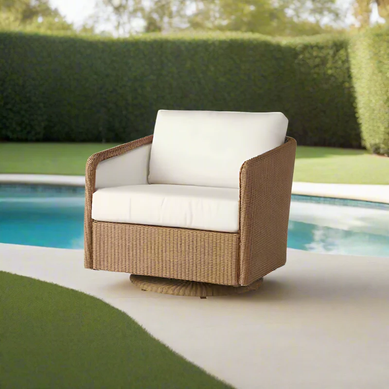Brown wicker chair with white cushions by a poolside