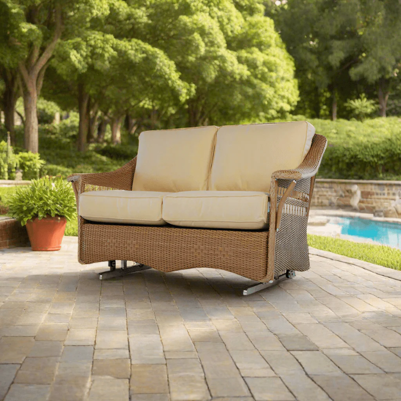 Wicker outdoor sofa with beige cushions on a patio near a pool