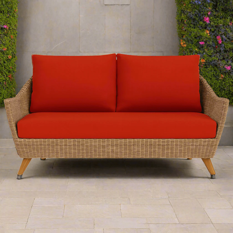 Wicker outdoor sofa with red cushions on a patio