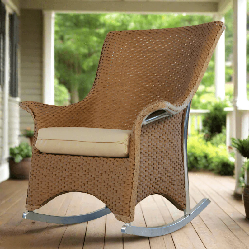 Brown wicker rocking chair on a wooden deck with a garden view