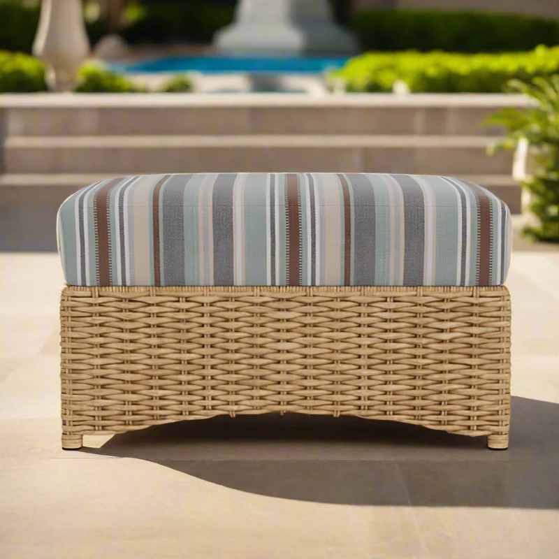 Wicker ottoman with striped cushion on a patio