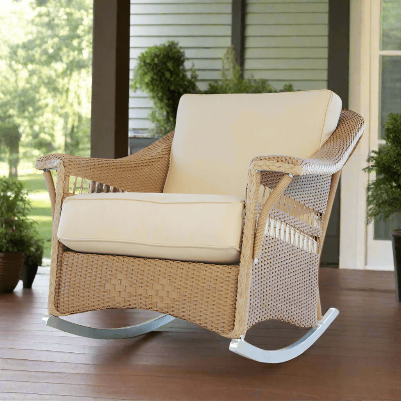 Wicker rocking chair with beige cushions on a wooden deck