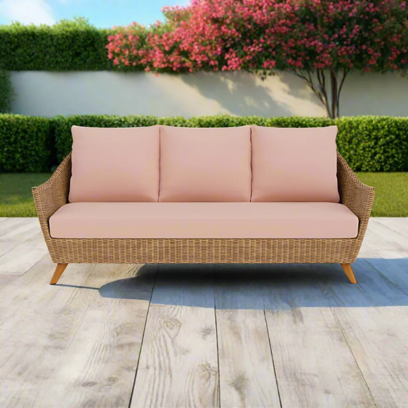 Wicker outdoor sofa with pink cushions on a wooden deck