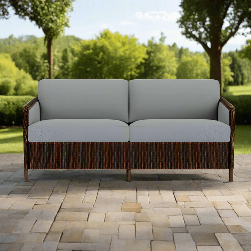 Outdoor sofa with wicker frame and light gray cushions on a patio
