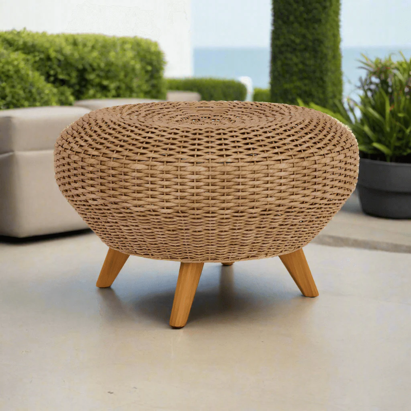 Woven stool with wooden legs on a patio with greenery and ocean view