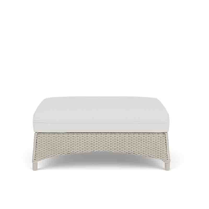 Wicker ottoman with a white cushion on a white background