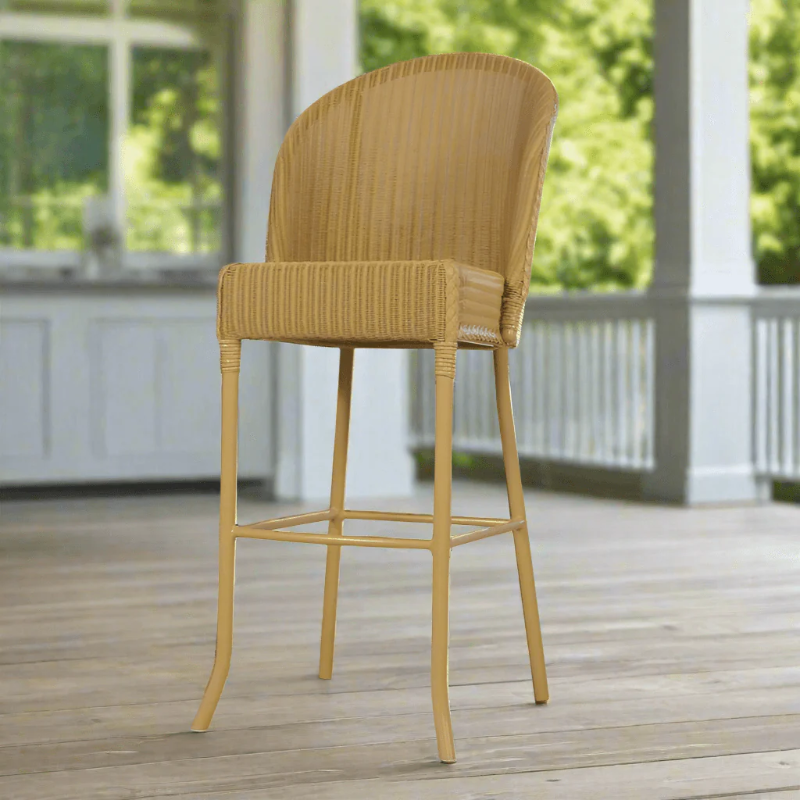 Wicker bar stool on a wooden deck with greenery in the background