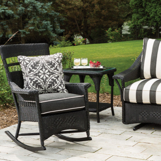 Outdoor patio set with wicker chairs, cushions, and a small table on a patio.