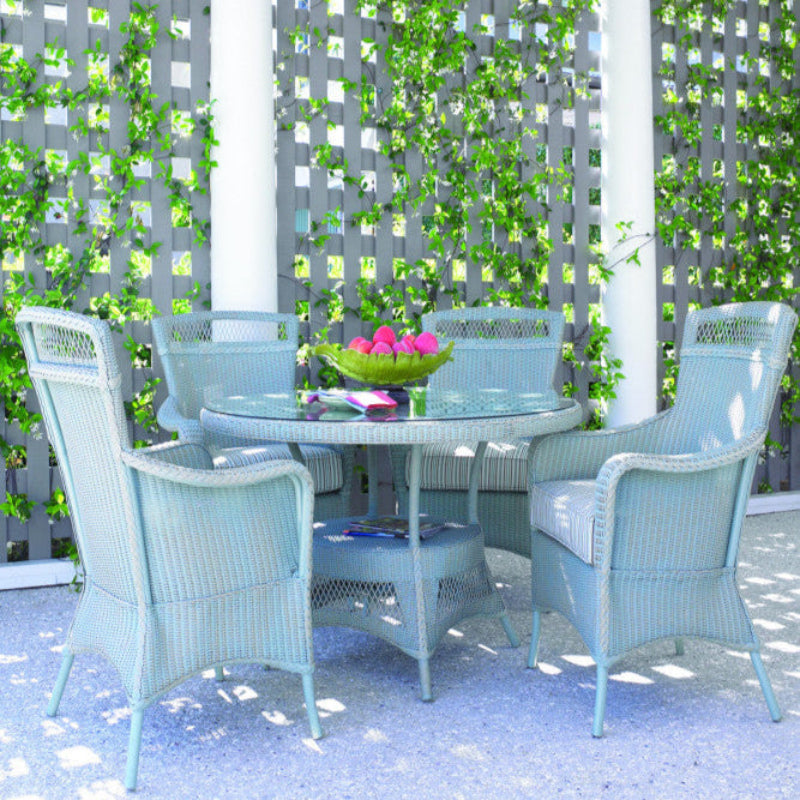 Outdoor patio set with a table and chairs against a green lattice wall.