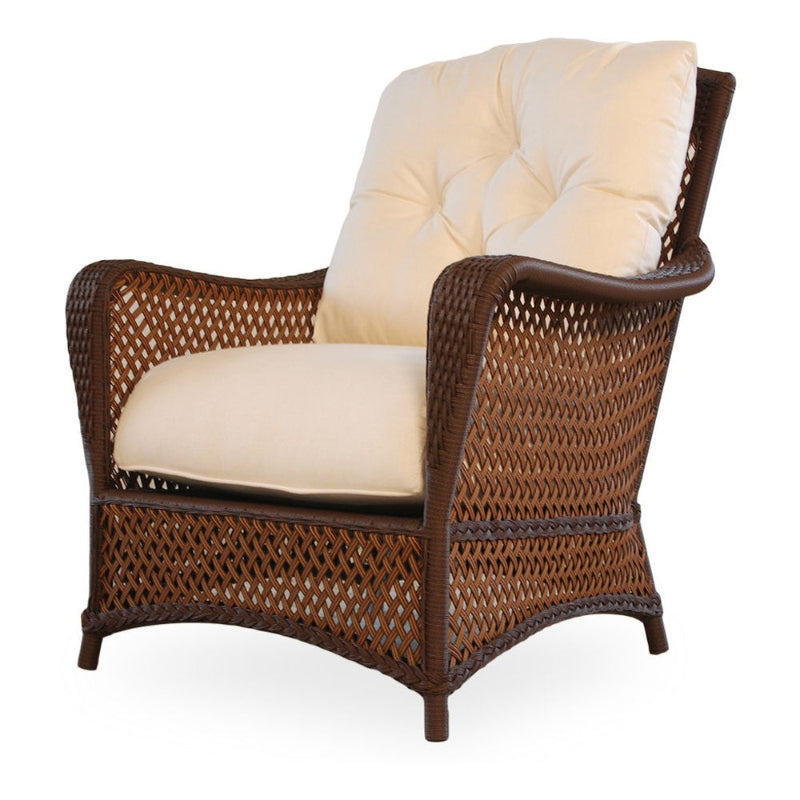 A Lloyd Flanders Grand Traverse Wicker Lounge Chair with a brown wicker frame and a white cushion.